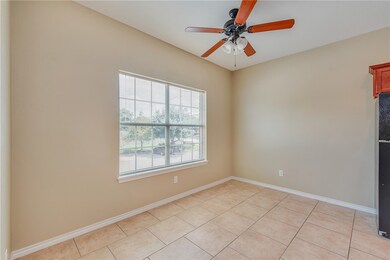 Empty room with a ceiling fan and light tile patte