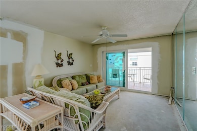 Living area with a textured ceiling, a ceiling fan, and unfinished concrete floors