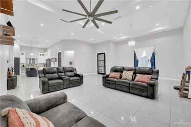Living room featuring a raised ceiling and ceiling fan with notable chandelier