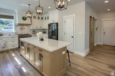Kitchen with a barn door, premium range hood, tasteful backsplash, pendant lighting, and stainless steel appliances
