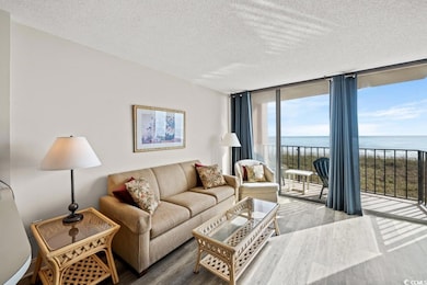 Living area with a water view, wood finished floors, floor to ceiling windows, a textured ceiling, and healthy amount of natural light