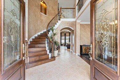 The two-story foyer welcomes you into the warmth and sophistication of this home where no detail is overlooked. You are instantly greeted with double crown molding, diagonal tile flooring, elegant chandelier, a winding staircase with wood treads and iron balusters, a decorative stairway art niche, and dramatic arched entryways.  The Study is to the left, and the Formal Dining is to the right, and you have straight views from the Foyer all the way into the Den and backyard beyond.
