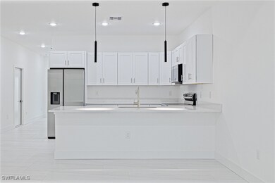 Kitchen with light countertops, white cabinets, a