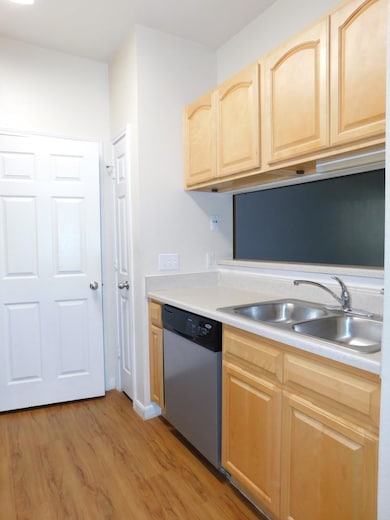 Kitchen with light brown cabinets, light countertops, dishwasher, and light wood-style floors