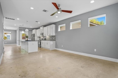 Kitchen with dark countertops, open floor plan, plenty of natural light, white cabinetry, and recessed lighting