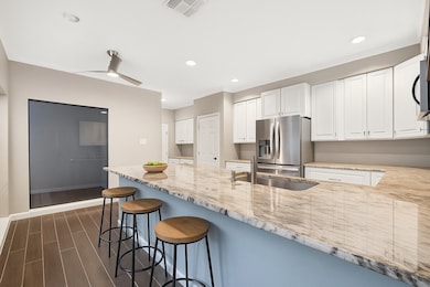 Bright and modern kitchen featuring granite-look countertops, stainless steel appliances, and a spacious peninsula with seating for casual dining (virtually staged).