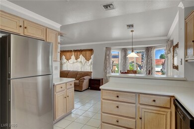 Kitchen with freestanding refrigerator, light brown cabinetry, dishwashing machine, open floor plan, and light tile patterned floors