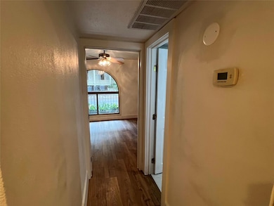 Hallway with dark wood-style flooring and a textured wall