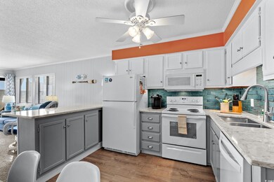 Kitchen featuring gray cabinetry, a sink, a textured ceiling, and white appliances
