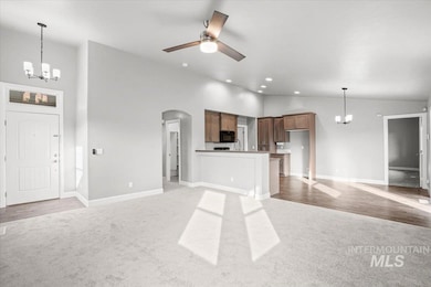 Unfurnished living room with a chandelier, light carpet, arched walkways, ceiling fan, and recessed lighting