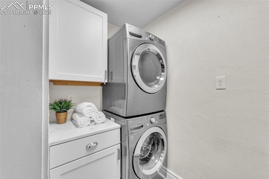 Laundry area featuring stacked washer / dryer and cabinet space
