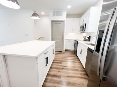 Kitchen featuring white cabinetry, stainless steel