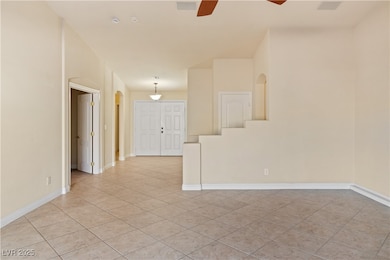 Living room featuring light tile patterned flooring, arched walkways, and a ceiling fan