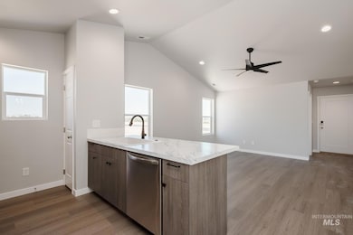 Kitchen featuring dishwasher, a peninsula, a ceiling fan, light wood-type flooring, and lofted ceiling
