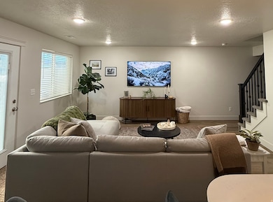 Living area featuring a textured ceiling, stairs, and wood finished floors