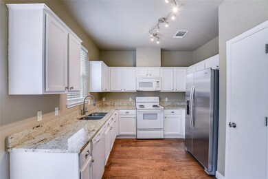 Kitchen with white appliances, a sink, white cabi