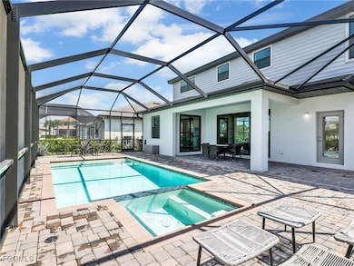 View of pool with a sunroom, a pool with connected hot tub, a patio, and a lanai