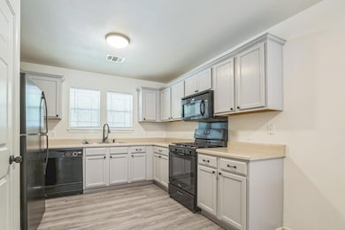 Kitchen with black appliances, light countertops, and light wood-type flooring