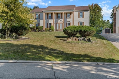 Neoclassical / greek revival house with a front yard and an outbuilding