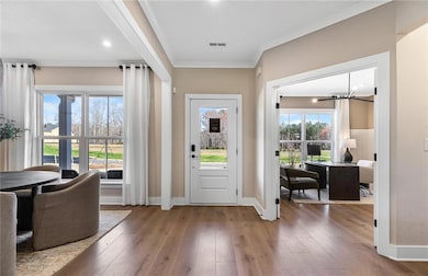 Foyer entrance featuring hardwood / wood-style floors, crown molding, and a chandelier