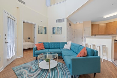 Living room featuring light wood-type flooring and a towering ceiling