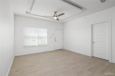 Spare room featuring ceiling fan, visible vents, a raised ceiling, baseboards, and light wood-style flooring