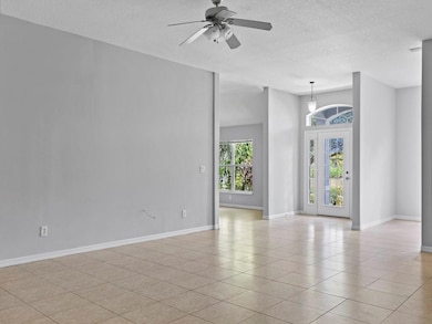 Empty room featuring light tile patterned floors, a textured ceiling, and ceiling fan