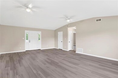 Unfurnished living room with ceiling fan, vaulted ceiling, baseboards, and wood finished floors