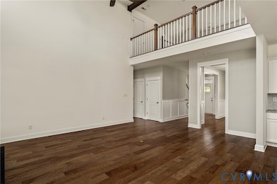 Unfurnished living room with dark wood finished floors and a high ceiling