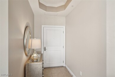 Hallway with a tray ceiling, baseboards, crown mol