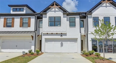 View of property featuring driveway, an attached garage, a standing seam roof, and board and batten siding