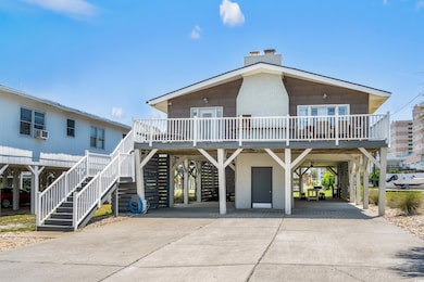 Raised beach house featuring a carport, concrete driveway, a chimney, and stairway