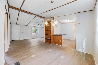 Unfurnished living room with light wood-style flooring, a ceiling fan, and a chandelier