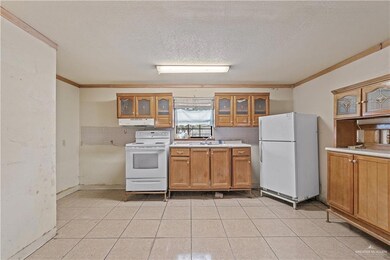 Kitchen with white appliances, crown molding, sink, decorative backsplash, and a textured ceiling