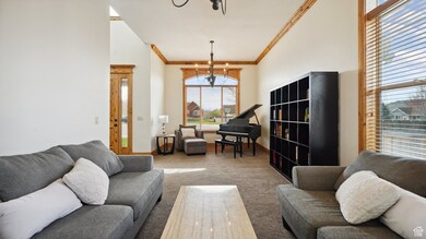 Living area featuring an inviting chandelier, crown molding, carpet flooring, and baseboards