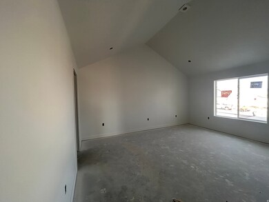 Empty room featuring lofted ceiling and unfinished concrete flooring