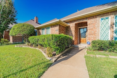 View of front of home featuring a shingled roof, a front yard, brick siding, and a chimney