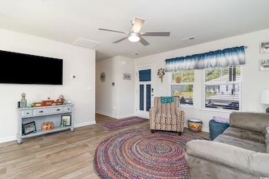 Living room featuring visible vents, light wood-st