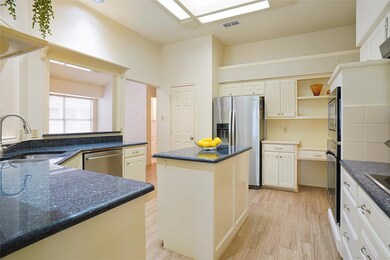 Kitchen featuring a kitchen island, light hardwood / wood-style flooring, stainless steel appliances, dark stone countertops, and sink