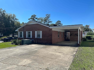 View of side of property with brick siding, driveway, and a lawn