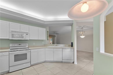 Kitchen with white appliances, white cabinetry, light countertops, light tile flooring, and ceiling fan