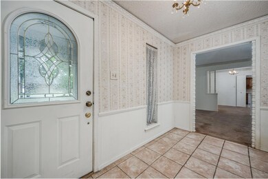Tiled foyer entrance featuring a notable chandelier, a textured ceiling, and crown molding