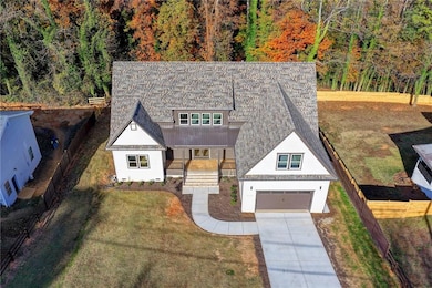 View of front facade featuring a porch, driveway, a garage, a metal roof, and a forest view