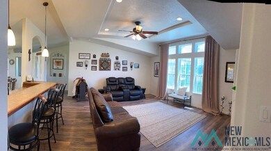 Living room featuring dark wood-type flooring, ceiling fan, recessed lighting, a tray ceiling, and a textured ceiling