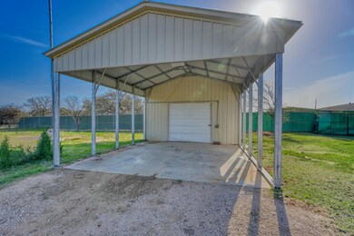 View of parking / parking lot with fence and a garage
