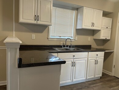 Kitchen featuring sink, white cabinetry, and dark 