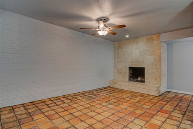 Unfurnished living room with a tiled fireplace and ceiling fan