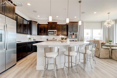 Kitchen with appliances with stainless steel finishes, decorative light fixtures, an island with sink, a breakfast bar, and decorative backsplash
