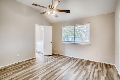 Empty room featuring lofted ceiling, light wood finished floors, and ceiling fan