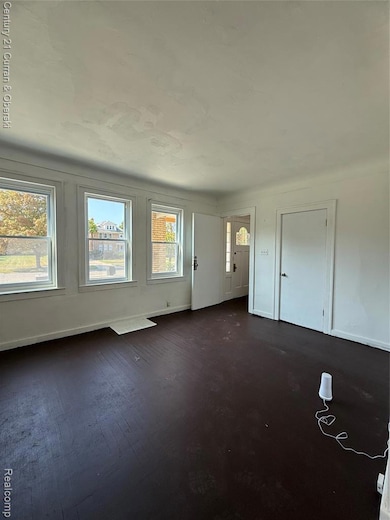 Spare room featuring baseboards and dark wood-style flooring